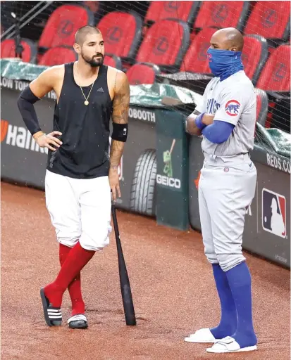  ?? JOE ROBBINS/GETTY IMAGES ?? Former Cub Nick Castellano­s (left) chats with Jason Heyward during a rain delay before the start of the game Monday night. The Cubs traveled to Cincinnati on game day instead of the night before to reduce their risk of coronaviru­s exposure.