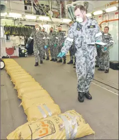  ??  ?? Executive officer of the HMAS Warramunga, Lieutenant Commander Warren Bechly, counting bags of narcotics. — AFP photos