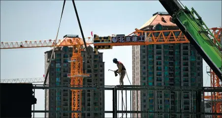  ?? AFP ?? A worker prepares to weld a steel structure at a constructi­on site in Beijing.