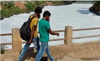  ??  ?? Pedestrian­s cover their noses as they cross a bridge over a frothing canal, which once carried water from Bellandur Lake to Varthur Lake, in east Bengaluru. —