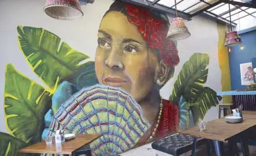  ??  ?? Latin flavor: Esqinita’s lanai features a wall mural with fan dancer.