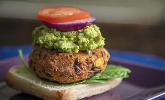  ?? Andrew Rush/Post-Gazette photos ?? A sweet potato-black bean burger on a ciabatta roll is topped with mashed avocado, red onion and tomato.