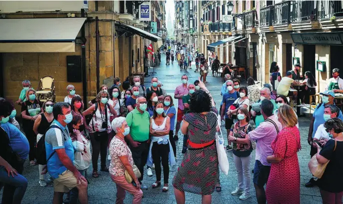  ?? EFE ?? En la imagen, un grupo de turistas, todos con mascarilla­s, visitan el casco antiguo de San Sebastián