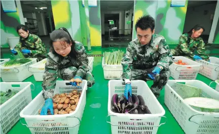  ?? PENG ZHAOZHI / XINHUA ?? Chen Kunyuan (second from right) and some of his employees sort vegetables before delivering them to customers in Nanchang, Jiangxi province.