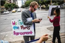  ?? TAMIR KALIFA/ AMERICAN-STATESMAN ?? Luke Metzger watches President Donald Trump’s announceme­nt that he will pull the U.S. from the Paris climate agreement on Thursday outside the Texas Capitol.