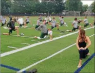  ?? JOHN KAMPF — THE NEWS-HERALD ?? Instructor Rachel Trem leads the Lake Catholic football team through a yoga session on Aug. 8.