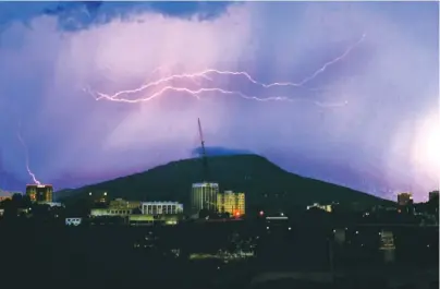  ?? STAFF FILE PHOTO BY TIM BARBER ?? Lightning bolts span the top of Lookout Mountain in July 2004 as a storm cloud moves west to east over Chattanoog­a. A single bolt appears to strike the SunTrust building, at left.