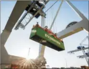  ?? AP FILE ?? A ship-to-shore crane lifts a 40-foot Evergreen Line shipping container off a jockey truck onto a container ship on June 19 at the Port of Savannah in Savannah, Ga.