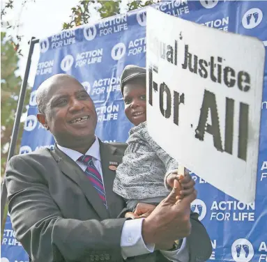  ??  ?? State Rep. Walt Blackman holds a sign that reads “Equal Justice For All” at the End Abortion Now rally on Friday.