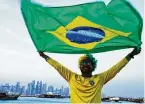  ?? JON GAMBRELL/AP ?? Brazil fan Ajmal Pial, of Khulna, Bangladesh, waves the Brazilian flag in Doha, Qatar, Friday. Fans poured into Qatar on Friday ahead of the Middle East’s first World Cup.