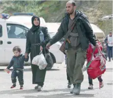  ?? — AFP ?? A Syrian rebel fighter and his family arrive in the village of Qalaat al Madiq, north of Hama after being evacuated from Eastern Ghouta following a deal.