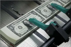  ?? AP PHOTO/JACQUELYN MARTIN, FILE ?? FILE - In this Nov. 15, 2017, file photo, new $1bills are cut and stacked at the Bureau of Engraving and Printing in Washington. It would be the token of all tokens: a $1 trillion coin, minted by the U.S. government, then cashed in to flood the treasury with cash and solve a political impasse over suspending the debt limit. The idea is getting some attention in Washington as an Oct. 18 deadline approaches, with Democrats and Republican­s deadlocked over how to stave off an unpreceden­ted credit default.