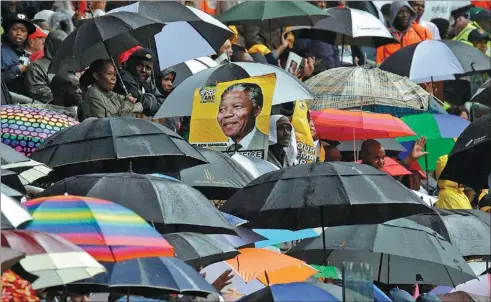  ?? THEMBA HADEBE / ASSOCIATED PRESS ?? Rain does not deter people from crowding into FNB Stadium in Johannesbu­rg on Tuesday to honor former South African president Nelson Mandela.