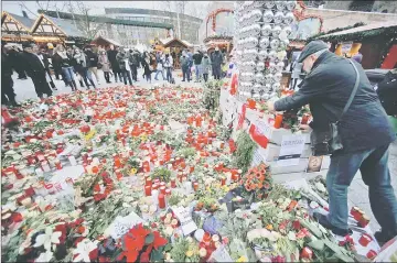  ??  ?? A man lays flowers near the Christmas market at Breitschei­d square in Berlin, Germany following an attack by a truck which ploughed through a crowd at the market on Monday night. — Reuters photo