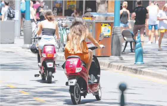  ?? Picture: RICHARD GOSLING ?? Glitter Strip shopkeeper­s say the number of scooter riders without helmets has exploded.