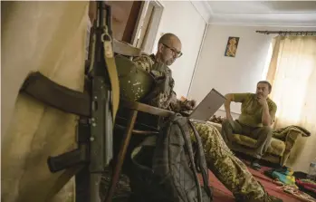  ?? JIM HULYEBROEK/THE NEW YORK TIMES ?? Anton Filatov, left, a Ukrainian film critic-turned-soldier, sits in an abandoned house Aug. 27 near the front lines in Donbas. He now writes movingly of the struggles in the trenches instead of what’s on the screen.