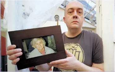  ??  ?? DISTRESS: Simon Cooke with a picture of his late mother who was badly neglected