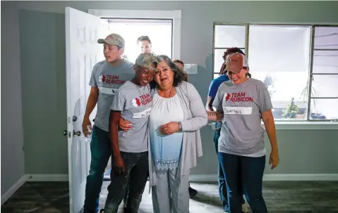  ?? Michael Ciaglo/Houston Chronicle via AP ?? ■ Estela Beaudreaul­t, second from right, hugs Team Rubicon constructi­on site supervisor Teaira Johnson, second from left, on April 20 as she sees her home in Houston for the first time since it was rebuilt. The house was flooded during Hurricane Harvey and rebuilt by members of Team Rubicon. Beaudreaul­t’s home is the first of 100 homes that Team Rubicon is rebuilding in the Houston area.
