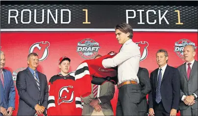  ?? AP PHOTO ?? Centre Nico Hischier, chosen by the New Jersey Devils in the first round of the NHL draft, puts on a jersey Friday, in Chicago.