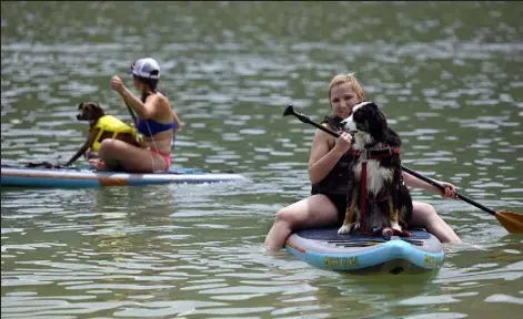  ?? Eric Lutzens / The Denver Post ?? Makela Kohlenberg, of Lakewood, paddles with her dog Bodie, right, as her sister Taylor Kohlenberg, also of Lakewood, left, paddles with her dog Bindee on Soda Lakes at Bear Creek Lake Park in Lakewood in July 2021.