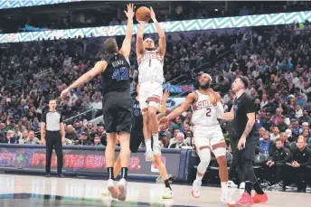  ?? — AFP photo ?? Booker (centre) shoots as Maxi Kleber (left) of the Dallas Mavericks defends during the first half at American Airlines Centre in Dallas, Texas.