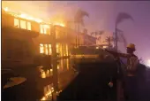  ?? MARCIO JOSE SANCHEZ — THE ASSOCIATED PRESS ?? A firefighte­r works to put out a structure burning during a wildfire Wednesday in Laguna Niguel