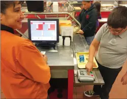  ?? AP PHOTO/MORGAN LEE ?? In this May 4 photo, Cafeteria worker Paula Herrera, left, supervises as second grade student Dylan Casias punches in his student identifica­tion number to deduct a meal payment at Gonzales Community School in Santa Fe, N.M. All students are offered the...