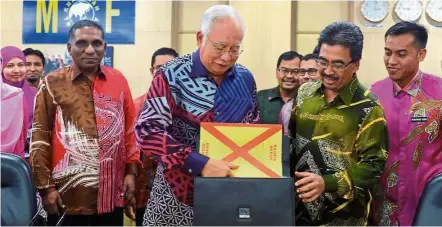  ??  ?? In the bag: Najib placing the Budget 2017 text into his briefcase while Finance Minister II Datuk Johari Abdul Ghani (second right) looks on. With them are Treasury secretary-general Tan Sri Dr Mohd Irwan Serigar Abdullah (left) and Finance Ministry...