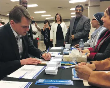  ?? ERIN PETROW ?? Saskatoon Mayor Charlie Clark signs the United Nations’ #WithRefuge­e petition at the Open Door Society’s WEconnect job fair at TCU Place in Saskatoon on Thursday.