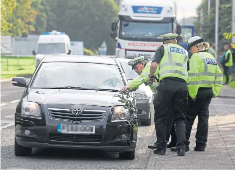  ??  ?? Police examine a car at the scene of the incident at West Pitkerro Industrial Estate this morning.