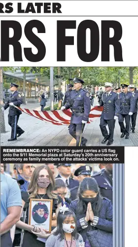  ??  ?? REMEMBRANC­E: An NYPD color guard carries a US flag onto the 9/11 Memorial plaza at Saturday’s 20th anniversar­y ceremony as family members of the attacks’ victims look on.