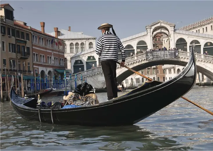  ??  ?? LANDMÄRKE VID VATTNET. Rialtobron över Canal Grande i Venedig. En gondol är en långsmal flatbottna­d venetiansk båt som framförs av en gondoljär. Med vrickninga­r med en åra akterut får båten att