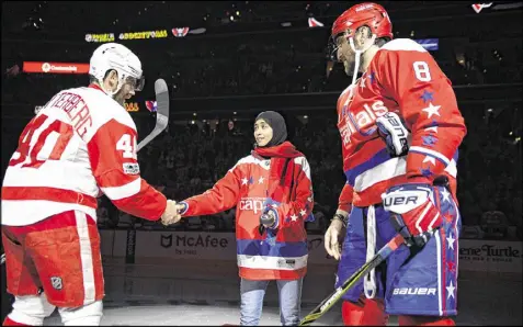  ?? NICK WASS PHOTOS / AP ?? Fatima Al Ali of the United Arab Emirates shakes hands with the Red Wings’ Henrik Zetterberg after a ceremonial puck drop before a game between Detroit and Washington. At right is the Capitals’ Alex Ovechkin.