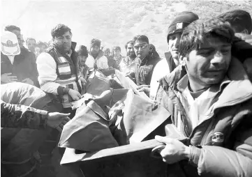  ?? — Reuters photo ?? Medics and rescuers evacuate the body of a victim killed in the plane crash in Iran.