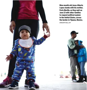  ?? GREGORY BULL/ AP ?? Nine- month- old Jesus Alberto Lopez stands with his mother, Perla Murillo, as they wait on June 13 with other families to request political asylum in the United States, across the border in Tijuana, Mexico.