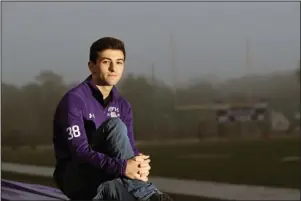  ?? The Associated Press ?? RUMSON, N.J: Dan Afflitto, a senior at Rumson-Fair Haven Regional High School, sits by the football field at his school in Rumson, N.J., on May 22. Dan, who graduates June 19, lost his father, for whom he is named, in the terror attacks of Sept. 11, 2001 — months before the younger Dan was born. He said he often thought of his dad during the national anthem before his football and basketball games. “It just made me want to play the best that I could,” he says.