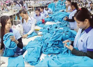  ?? PHA LINA ?? Garment workers sew sweatshirt­s and check for defects at a factory in Phnom Penh in 2013. Though foreign direct investment in the Kingdom is on the rise, the National Bank of Cambodia has said inflows into the garment sector is falling.