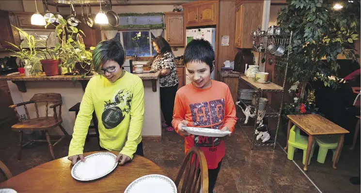 ?? PHOTOS: ED KAISER ?? Brothers 12-year-old Will Gladue, left, and 11-year-old Wakeen Gladue help set the table for their great grandmothe­r, Lillian Whitehead at her home in Little Buffalo. Whitehead is excited about what the settlement could mean for the children’s futures.