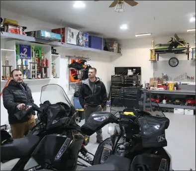  ?? Photo by Peter Loewi ?? PREP TIME— Jarvis and Jordan Miller prepare their sleds in their garage at home in Nome. Mounted on the wall is Jarvis’ first Kitty Kat snowmobile.