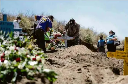  ?? Guillermo Arias - 9.jun.20/AFP ?? Parentes acompanham enterro de vítima de coronavíru­s em cemitério de Tijuana, no México