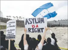  ?? AP PHOTO ?? Central American migrants sit on top of the border wall on the beach in San Diego during a gathering of migrants living on both sides of the border.