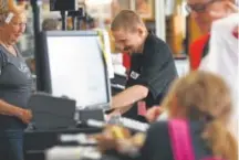  ??  ?? Cashier Seth Weshnak checks out a customer’s items at the Arc Thrift Store on West Colfax Avenue in Lakewood on Aug. 11.