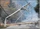  ??  ?? The Associated Press file People walk past a fallen transforme­r and power lines downed by a fire in Santa Rosa, Calif., on Oct. 10.