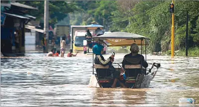  ??  ?? DIDI/SUMATERA EKSPRES/JPG TIMUR MATAHARI/AFP PHOTO ANTIMOGOK: Seorang warga asyik dengan HP saat naik dokar menembus banjir yang merendam jalanan Desa Bale Endah, Bandung, kemarin.