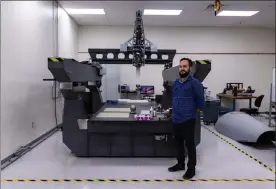  ?? ?? Senior Scientist Matt Skinner stands next to a one-of-a-kind 3D printer used by SI2 to print directly onto other equipment.