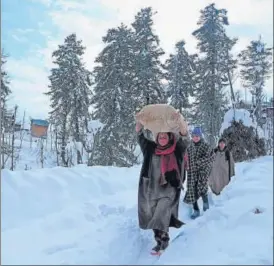  ?? AFP ?? Villagers carry rice after heavy snowfall in Budgam district of Srinagar on January 18.