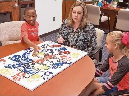  ?? R. Clayton McKee/ For the Chronicle ?? Frostwood Elementary pupil Daniel Patterson, principal Ellen Green and pupil Madeline Besetsny, talk about an antibullyi­ng painting project. A group of pupils created a painting of handprints to attract attention to the problem.