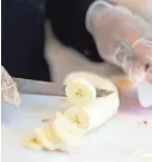  ??  ?? Katrina Carpenter slices bananas. Elise Dessert Company also offers strawberry banana and caramel banana pudding.
