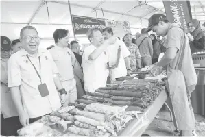  ?? — Gambar Chimon Upon ?? CERIA: Wee (kiri) mengiringi Dr Sim semasa lawatan ke bazar Ramadan MBKS di Stutong selepas mengagihka­n bubur lambuk semalam.