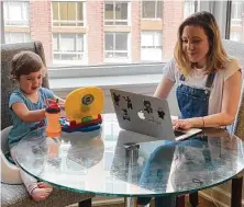  ?? Colin Nanka / Associated Press ?? Blake Ross, founder of Kindness of Strangers, works on her laptop as her daughter, Tess, 2, plays on her toy laptop.